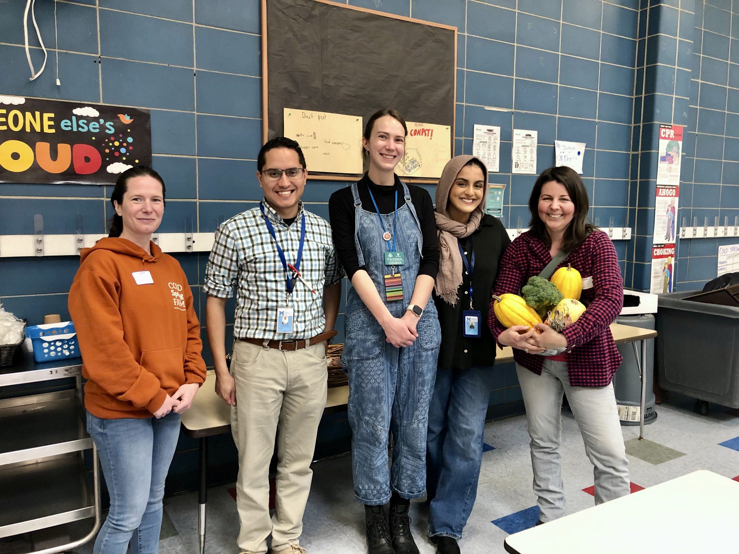 farmer and food service workers smiling in a cafeteria with produce