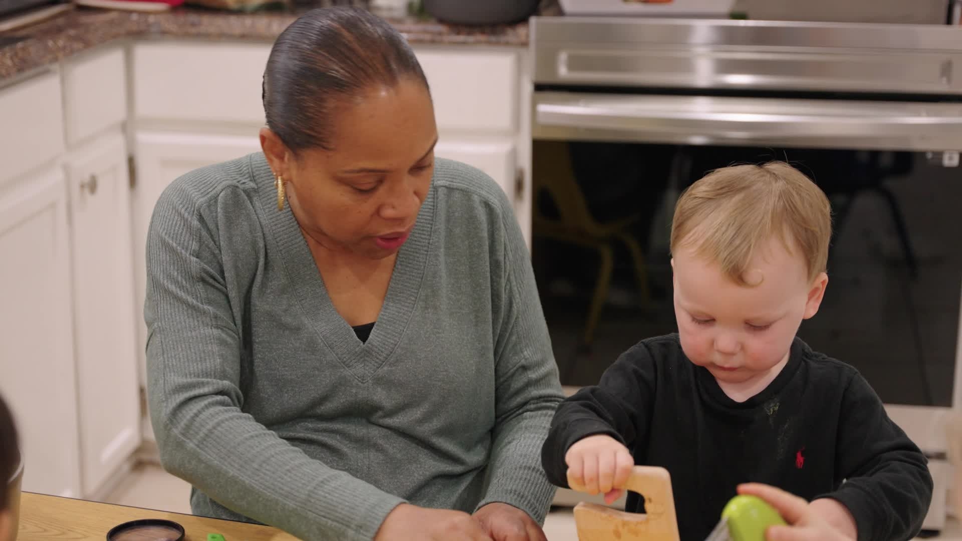 Woman teaching toddlers how to prepare sweet potatoes in a kitchen