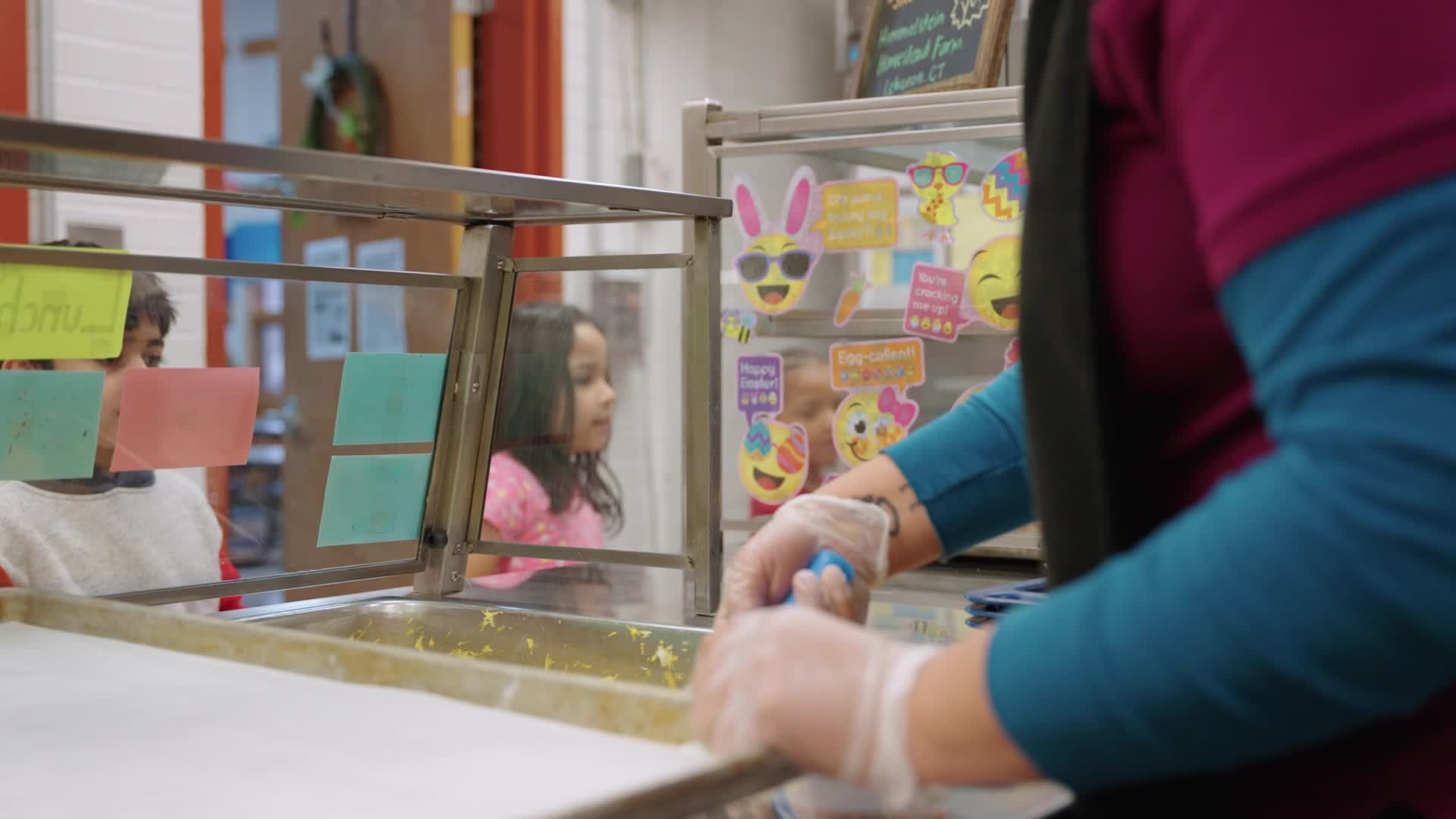 person serving food at an elementary cafeteria lunch line