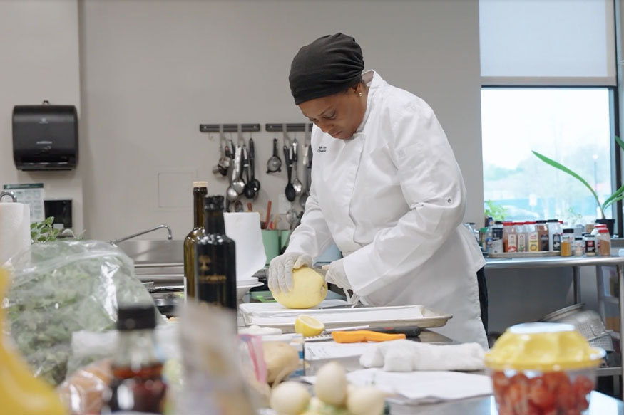 woman in a chef's coat preparing food in a kitchen