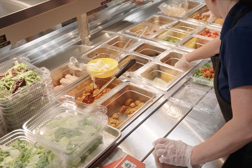 person serving food at an elementary cafeteria lunch line