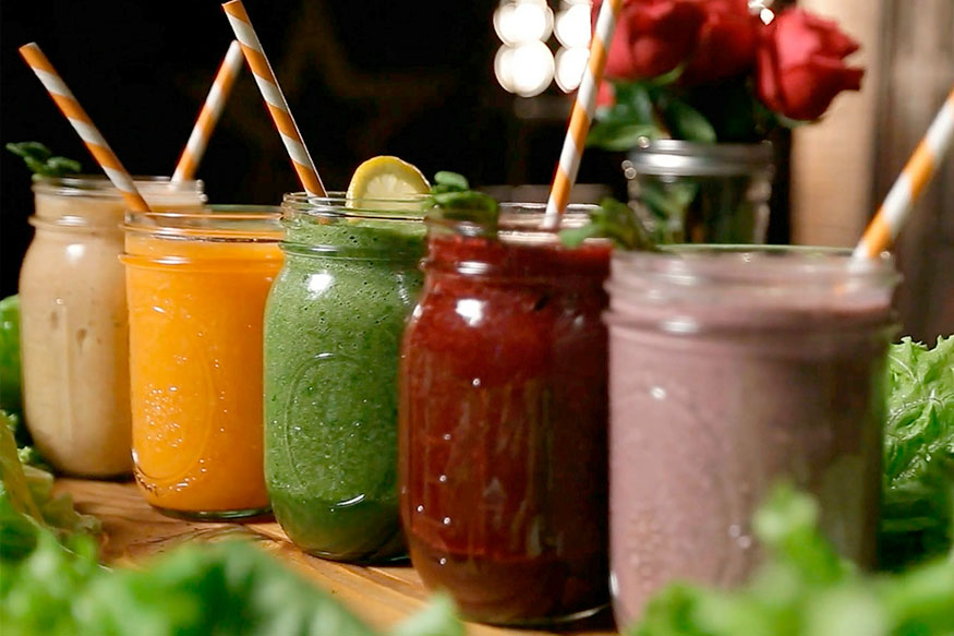 5 different smoothies in mason jars with straws.
