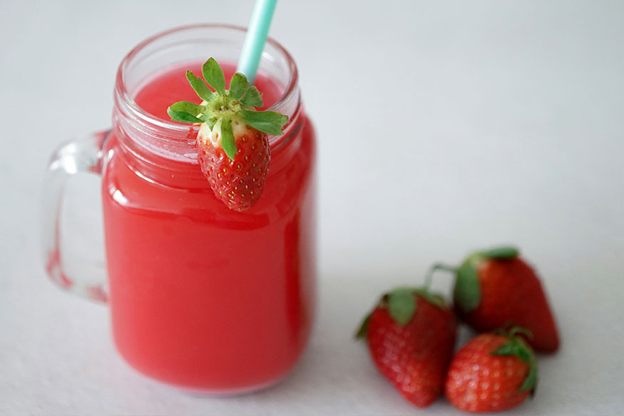strawberry soda in a cup with a straw and strawberries. 