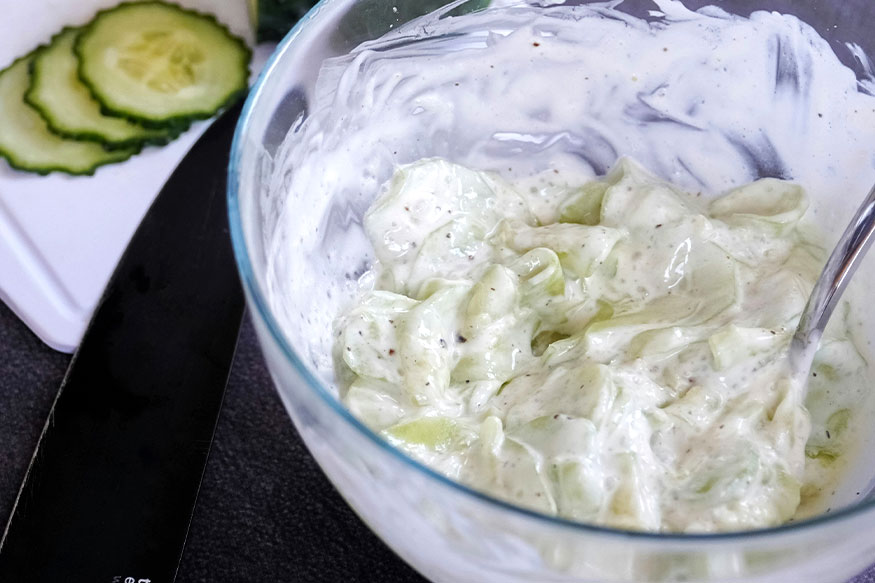 Tzatziki in a bowl with cucumber slices.