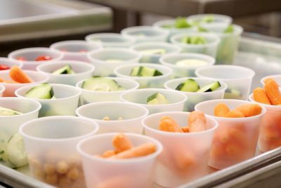 Cups on a tray filled with cut vegetables.